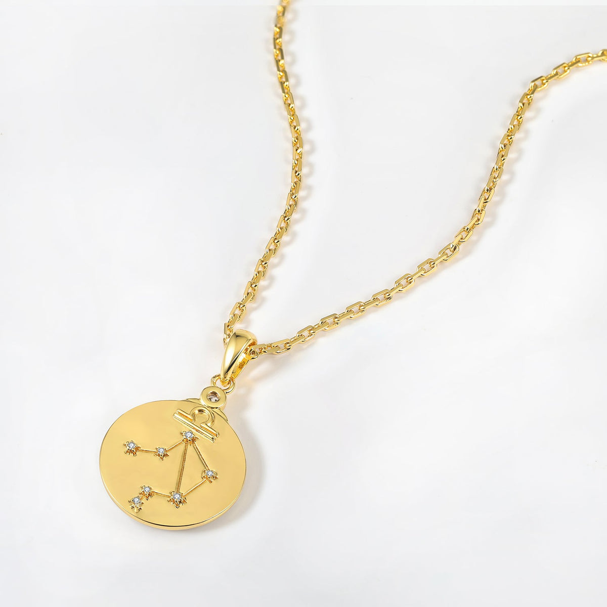 Gold and necklace with a zodiac Libra constellations pendant on a white background