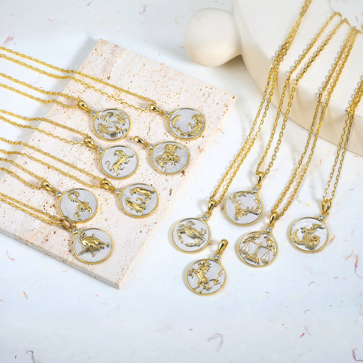 Gold necklaces with Gold and Silver zodiac pendants on a light surface