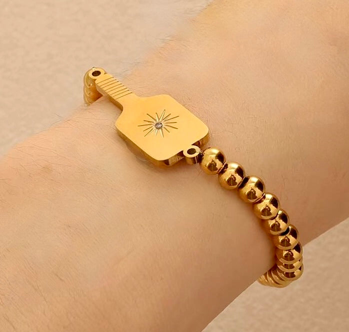 Picklebelle Gold beaded stretch bracelet with a pickleball paddle charm on a wrist