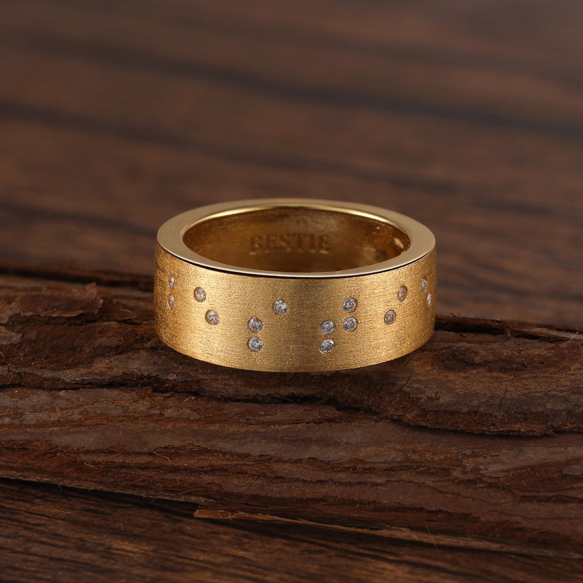 Touchstone Bestie Band Ring Brushed Gold Braille Message in Crystals and Etched Inside on wooden surface