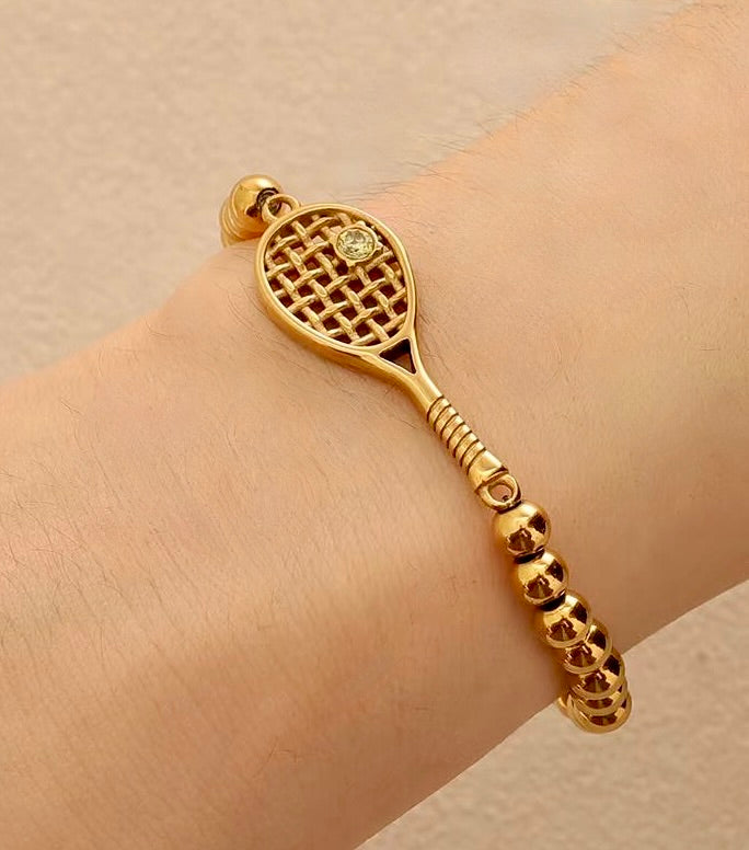 Lovematch Gold tennis racquet detail on beaded stretch bracelet on a model