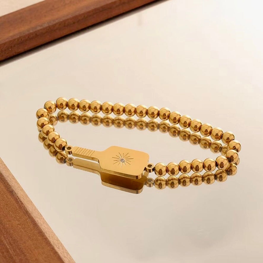 Picklebelle Gold beaded stretch bracelet with a pickle ball paddle charm