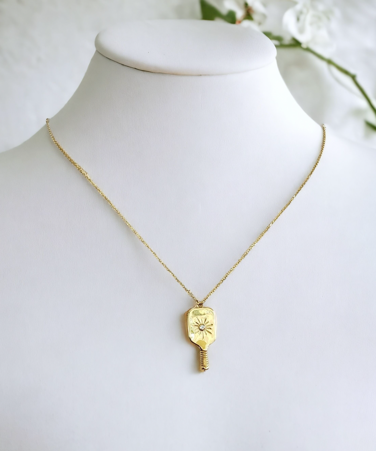 Gold necklace with a pendant on a mannequin against a white background