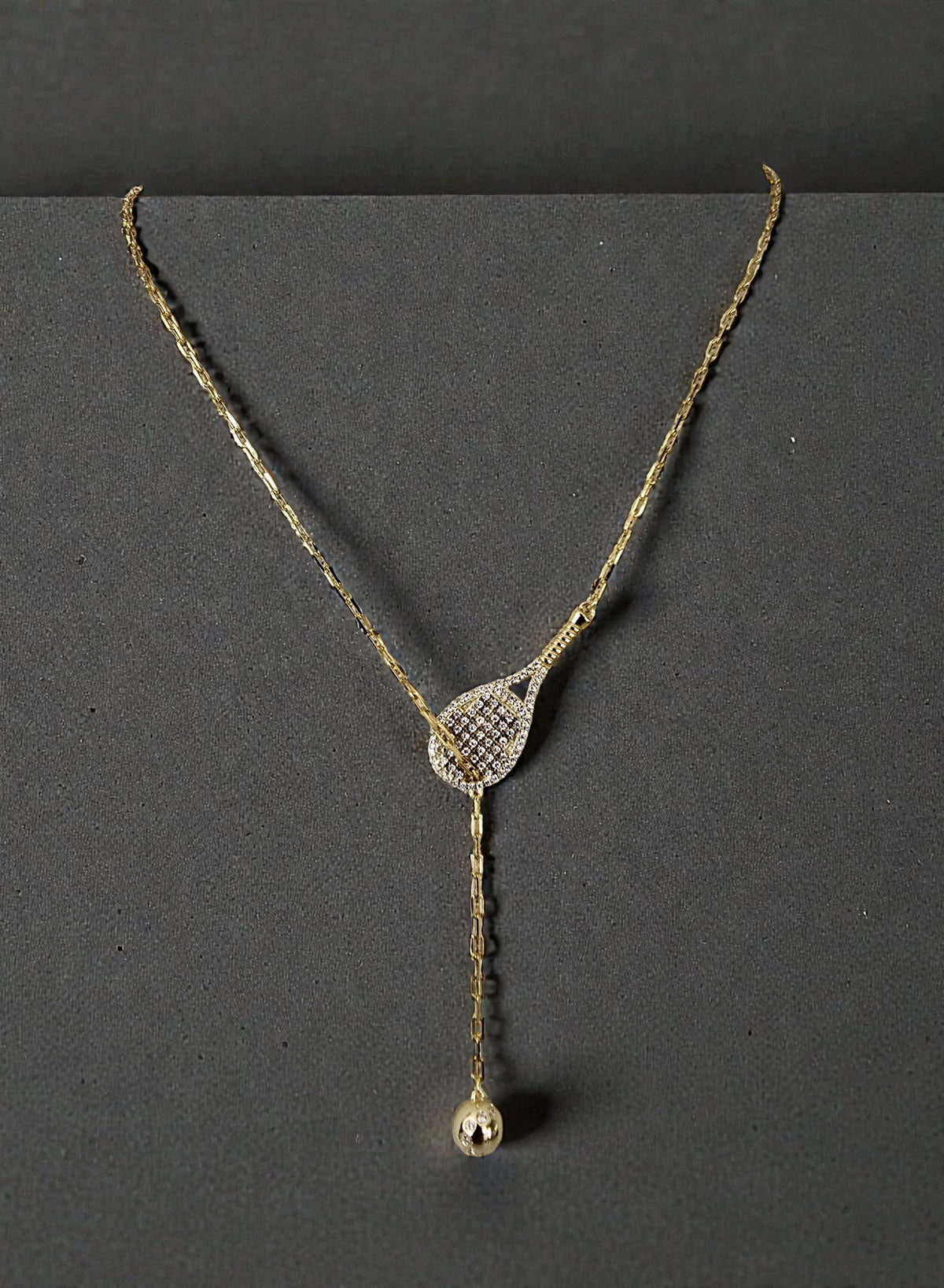 Delicate Gold Tennis Lariat necklace on a dark background
