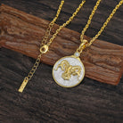 Gold and silver necklace with an Aries ram zodiac pendant on a wooden surface