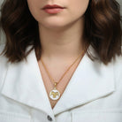 Woman wearing a gold necklace with an Aries ram pendant against a neutral background