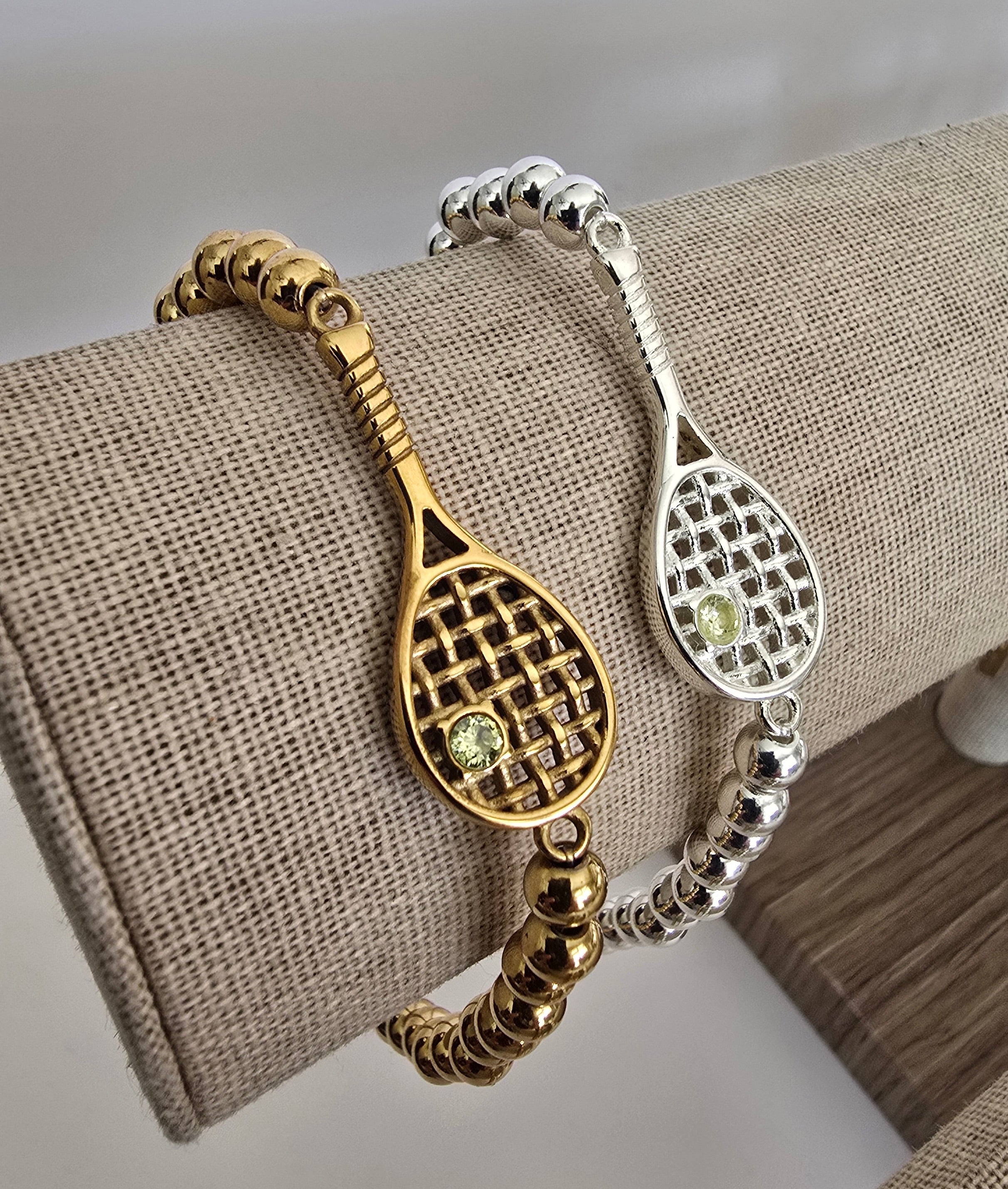 Two Lovematch stretch bracelets with tennis racquet designs on linen display