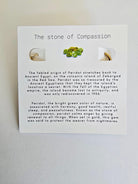 Peridot earrings on a card with descriptive text about the stone of compassion.
