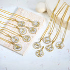Gold necklaces with twelve Gold and Silver zodiac pendants on a white surface