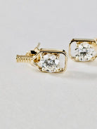 solid gold pickleball paddle stud earrings with a square bezel setting and a clear round-cut diamond, shown on a light neutral background.