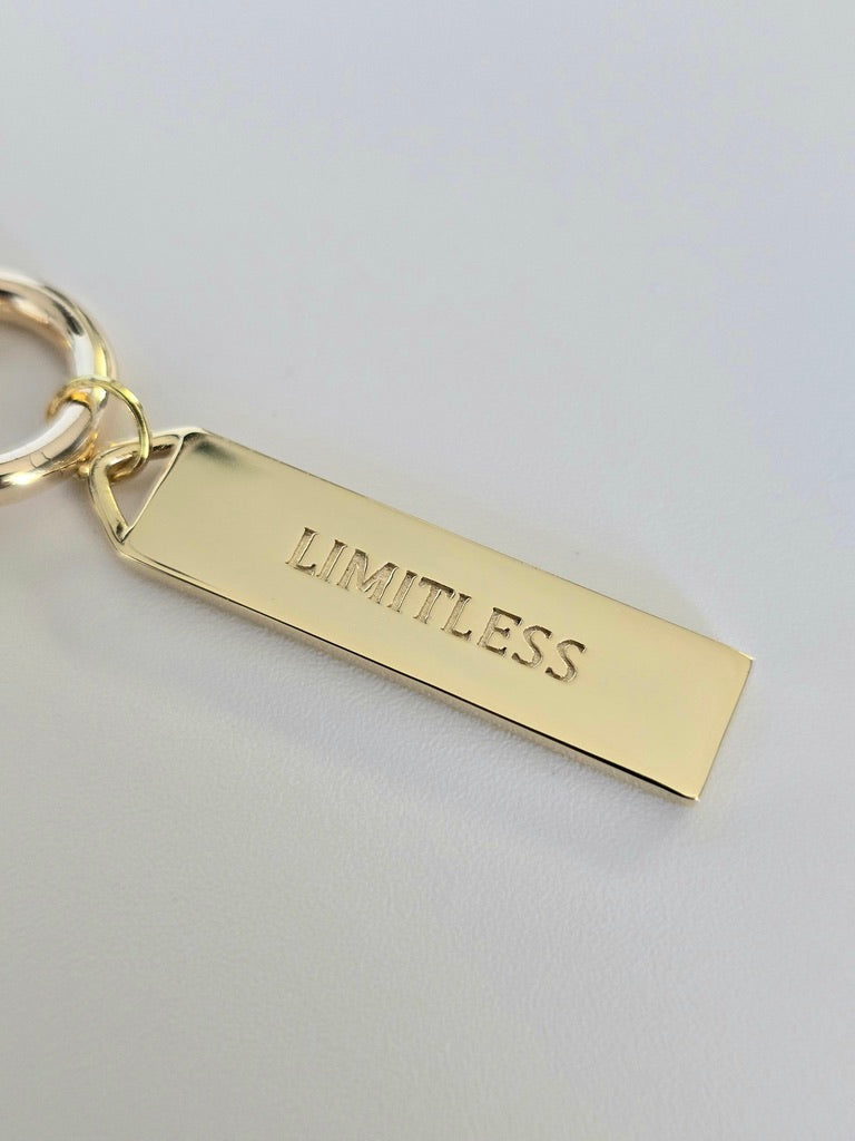 Gold keychain with 'LIMITLESS' tag on a light gray background