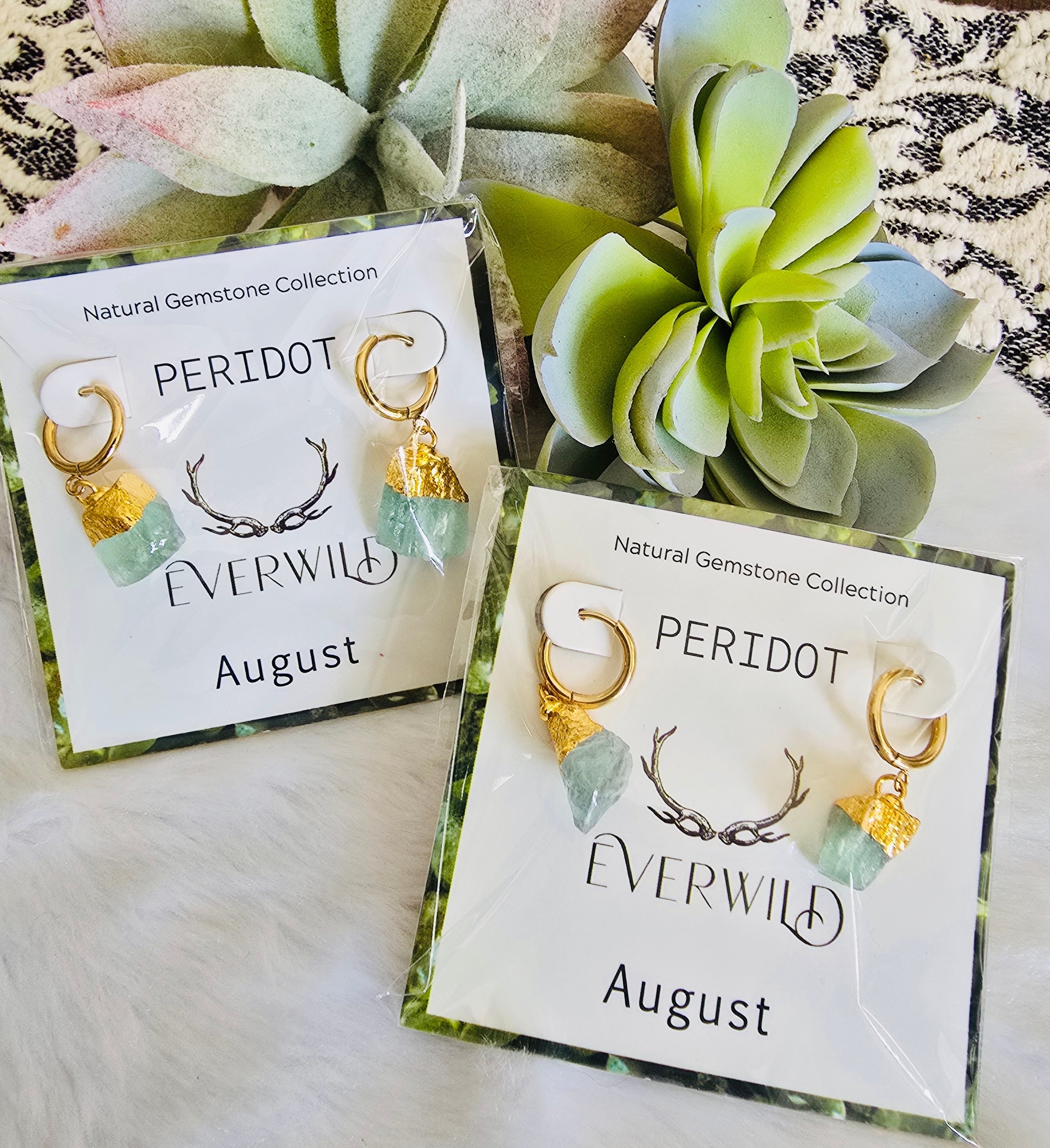 Peridot birthstone August earrings on cards with 'Everwild' branding and 'August' text, surrounded by greenery.
