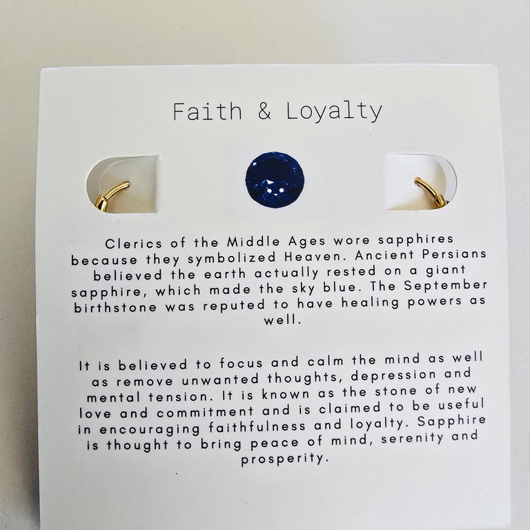 Sapphire earring on a card with 'Faith & Loyalty' text and sapphire information.