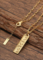Touchstone Beloved Bar Necklace Gold on wooden surface