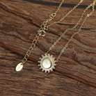 Saints Gold Necklace featuring a sunburst disc with friendship symbol etched into it, on a wooden background