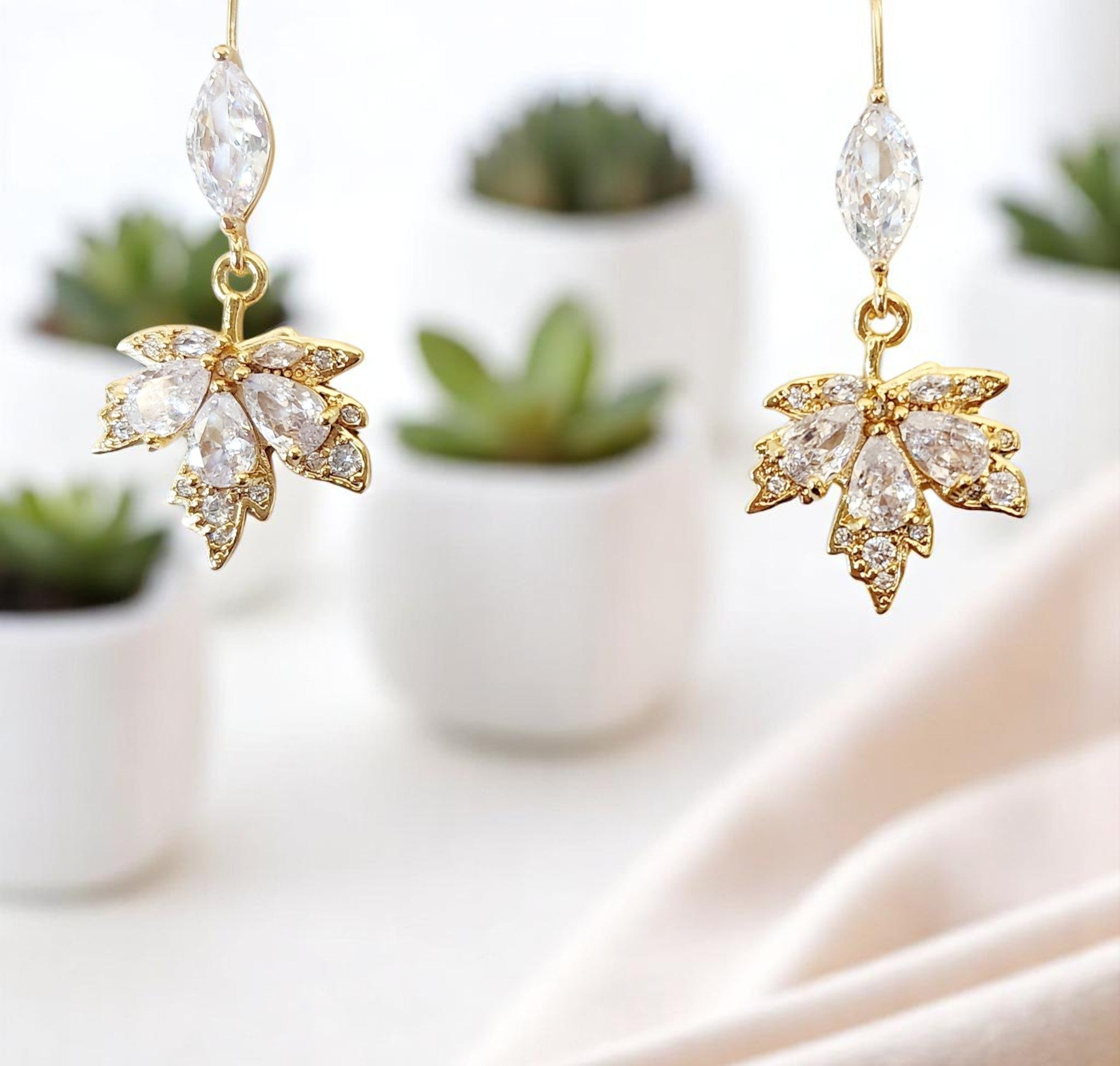 Gold maple leaf-shaped earrings with clear crystals